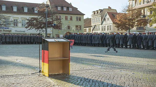 Szenario Dorfplatz mit leerem Rednerpult, im Hintergrund Soldaten der Bundesweh