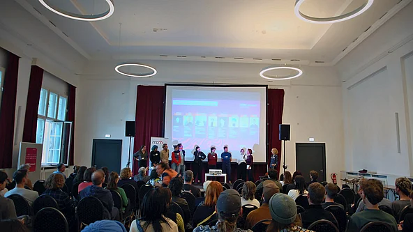 Saal mit Bühnenpräsentation und Publikum