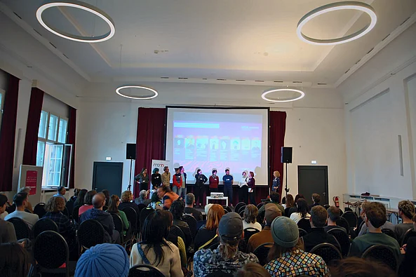 Saal mit Bühnenpräsentation und Publikum