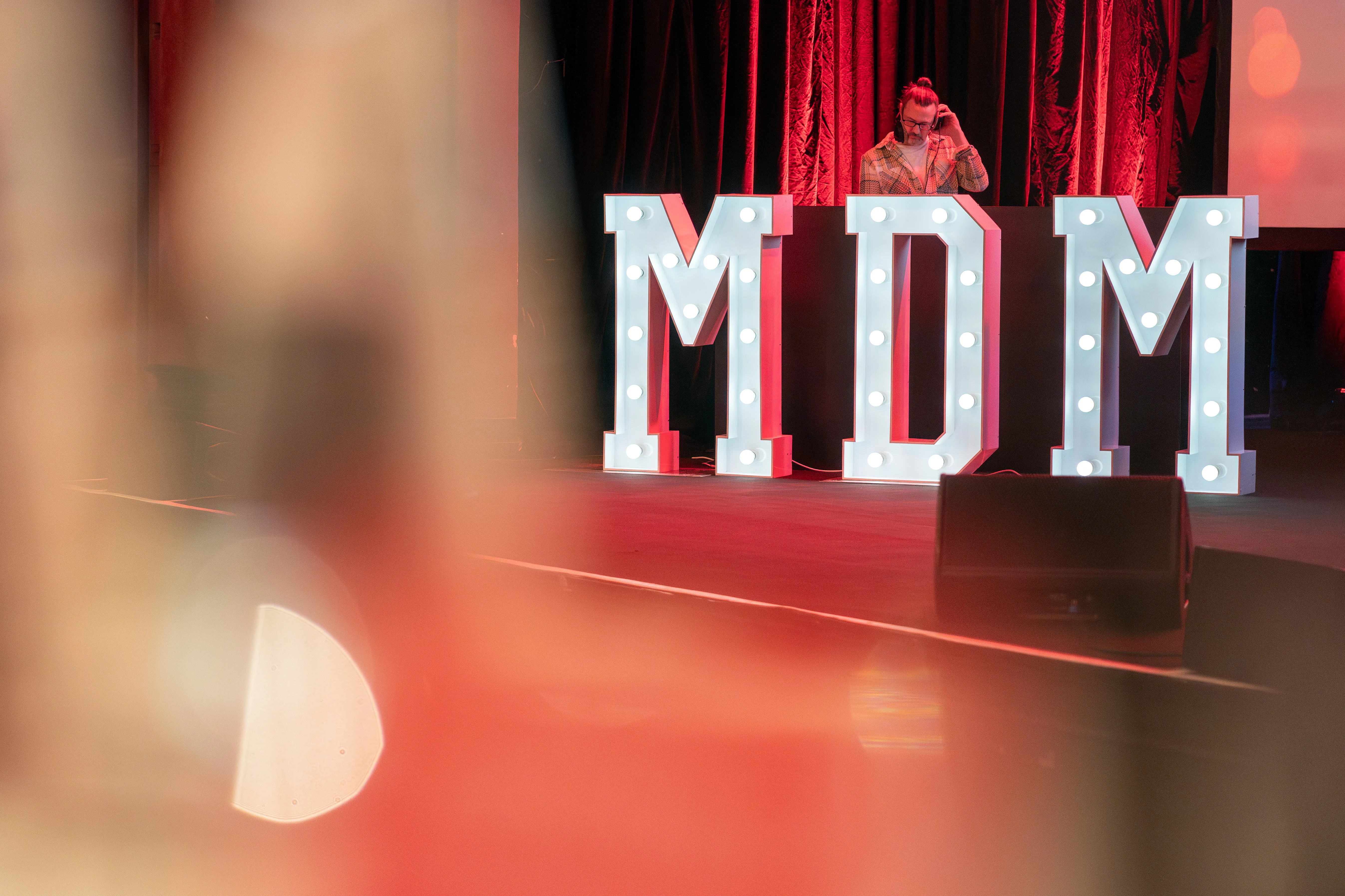MDM-Schriftzug auf Bühne mit DJ im Hintergrund