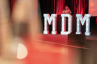 MDM-Schriftzug auf Bühne mit DJ im Hintergrund